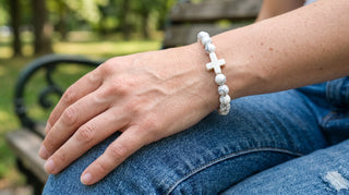Christliches Kreuz-Perlenarmband am Handgelenk einer jungen Frau