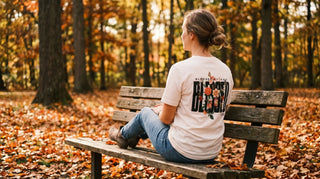 Junge Frau mit christlichem Pullover mit Rückenprint auf einer Parkbank im Herbst