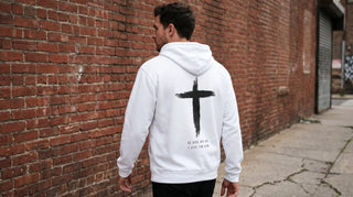 Mann von hinten mit christlichem Pullover mit Rückenprint an einer Backsteinwand