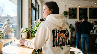 Junge Frau von hinten mit christlichem Hoodie mit Rückenprint am Cafefenster