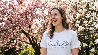 Junge Frau im Oster-Outfit mit christlichem Shirt unter blühenden Bäumen