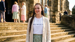 Frau im Ostersonntag-Look mit christlichem Shirt auf Kirchenstufen