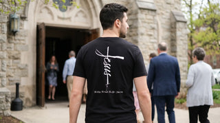Mann von hinten mit christlichem Shirt mit Rückenprint am Kircheneingang im Frühling