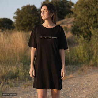 Frau traegt schwarzes Praise the Lord T-Shirt Kleid von Mountain Movers in der Natur (KI-generiertes Bild)