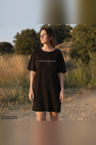 Frau traegt schwarzes Praise the Lord T-Shirt Kleid von Mountain Movers in der Natur (KI-generiertes Bild)