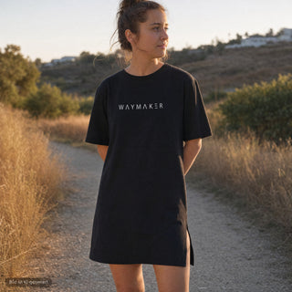 Frau traegt schwarzes Waymaker T-Shirt Kleid von Mountain Movers in der Natur (KI-generiertes Bild)
